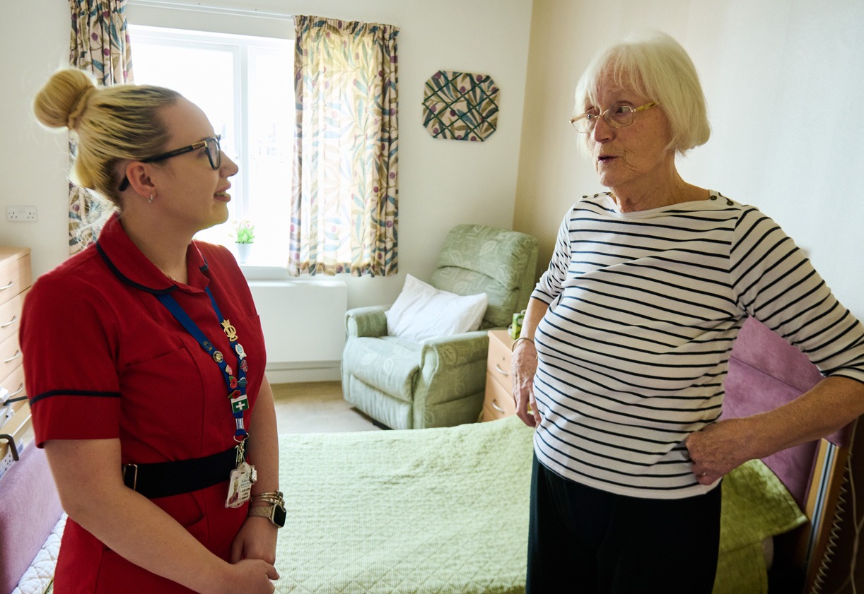 A nurse chatting with a resident in a bright, homely bedroom